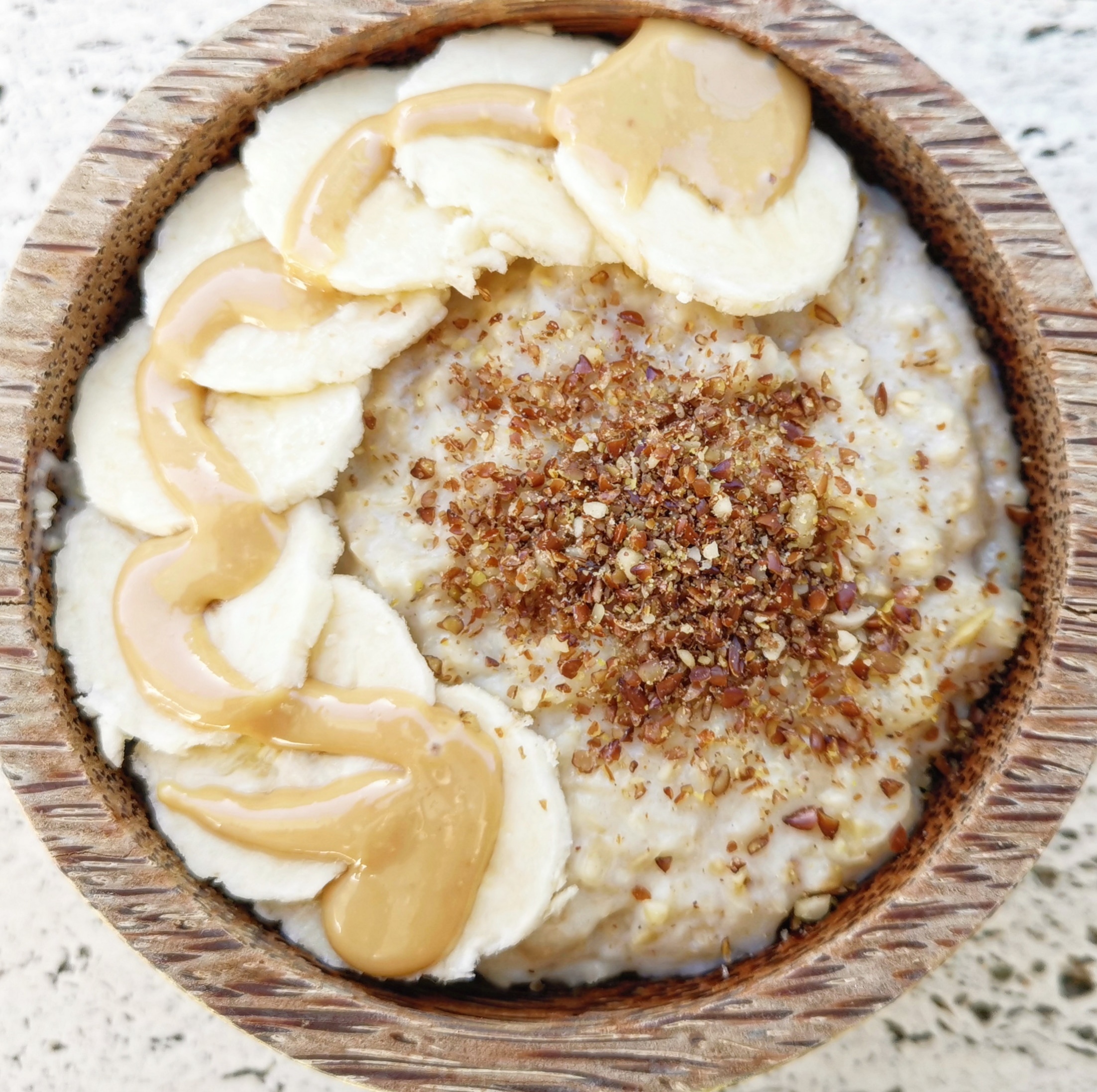 PORRIDGE D'AVOINE AVEC BANANE, BEURRE DE CACAHUÈTE ET MÉLANGE DE GRAINES MOULUES