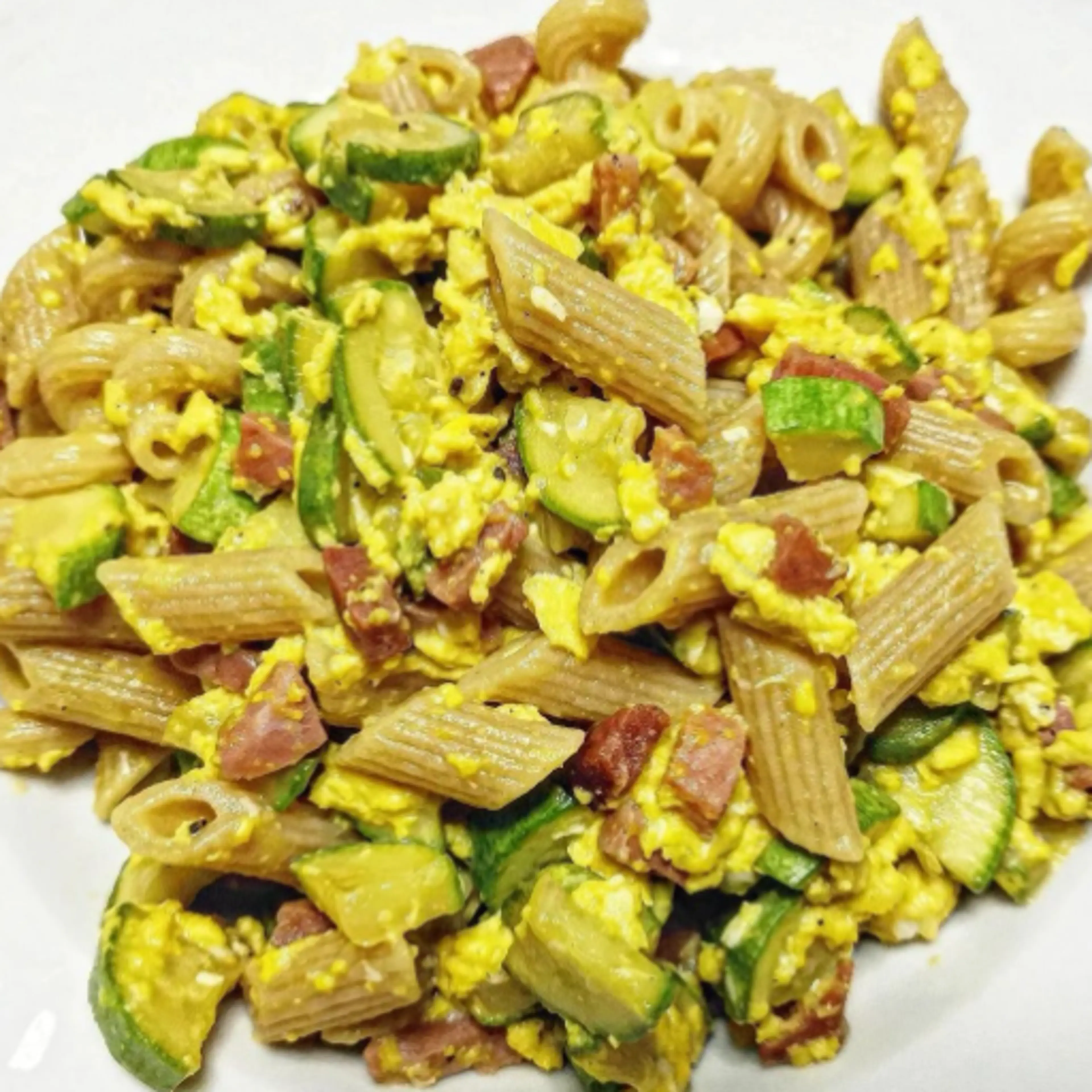 Wholemeal penne with eggs, speck and zucchini