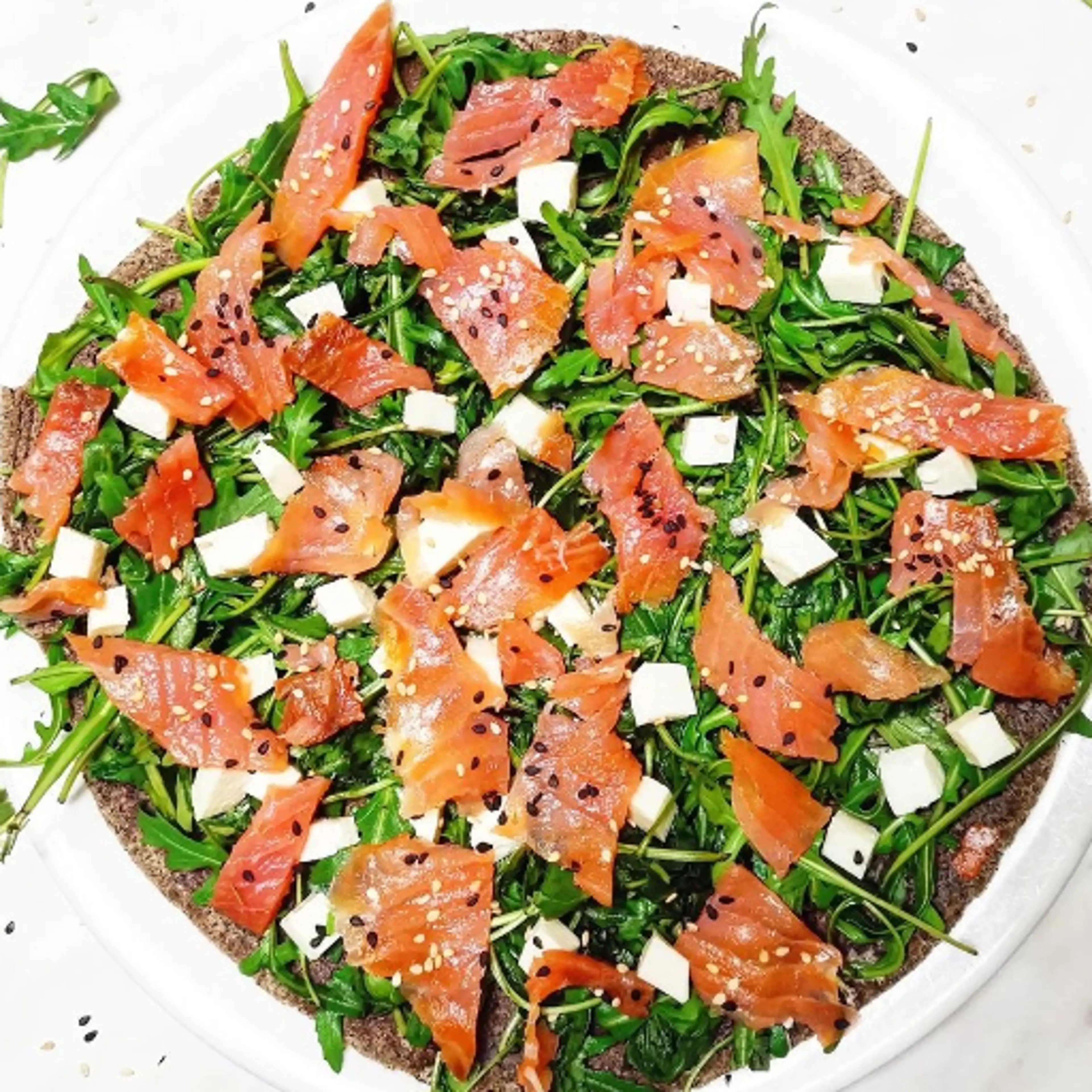 Homemade piadina with arugula, salmon, mozzarella and sesame seeds