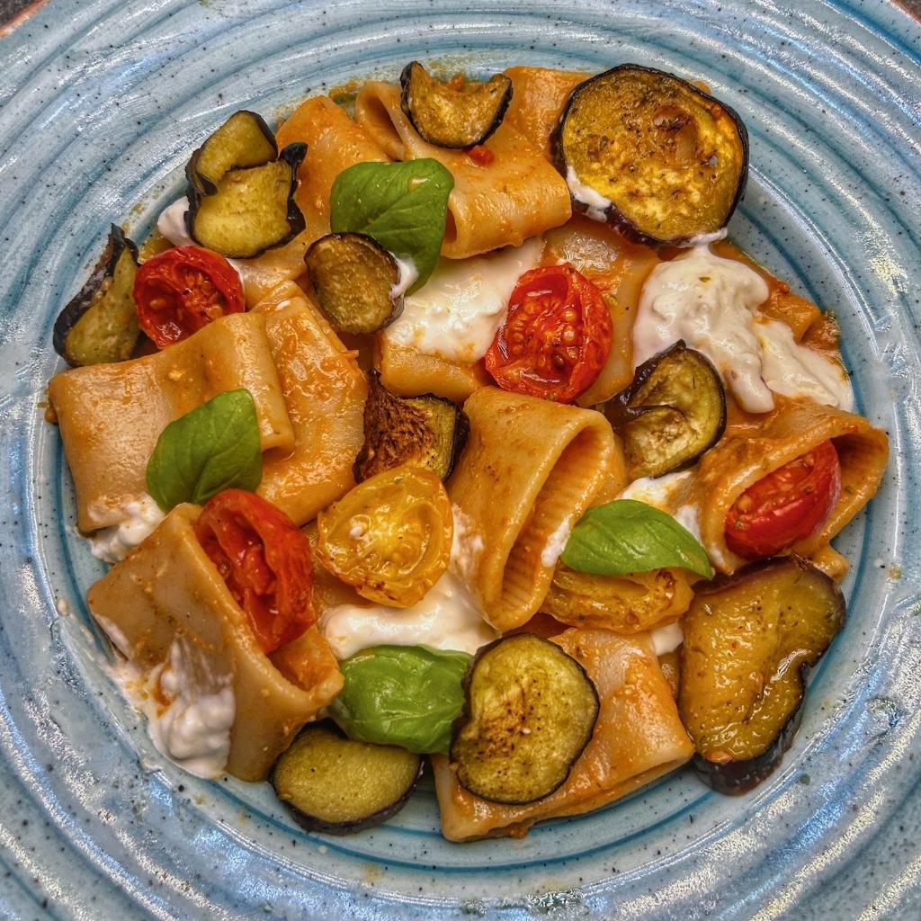 Mezze maniche alla salsa di datterini confit e pesto, con cips di melanzane, datterini e burrata