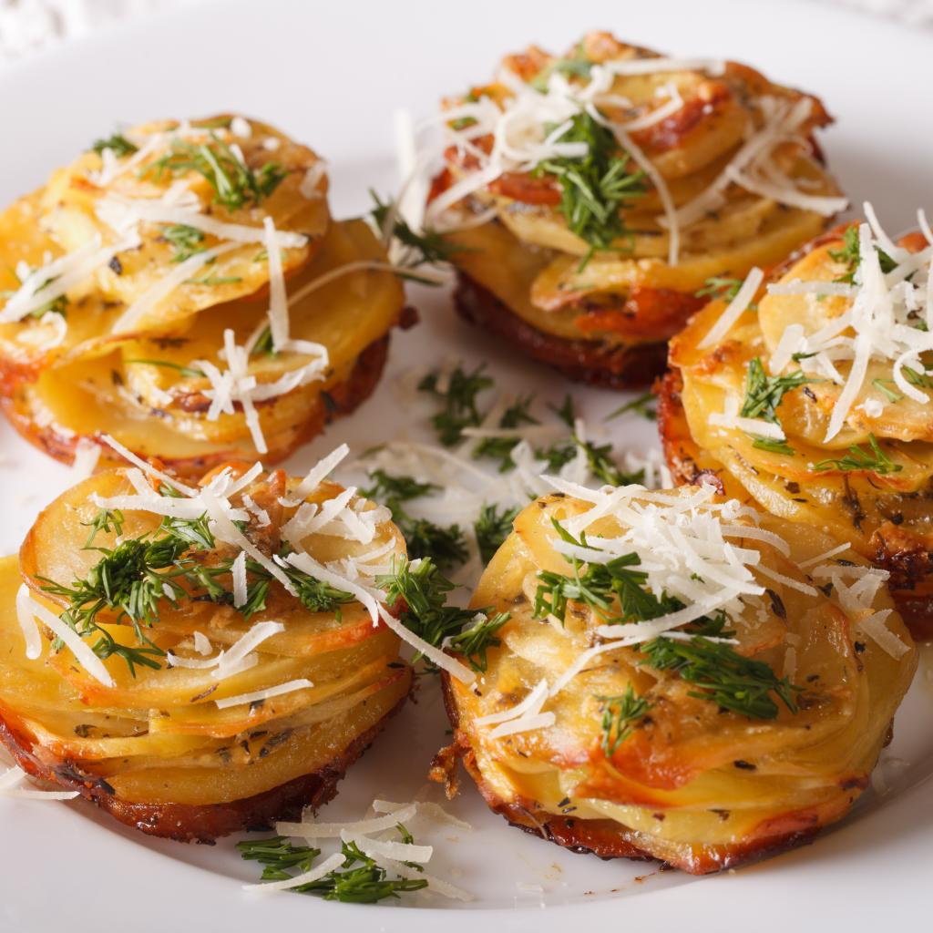 Nidi di patate al forno con formaggio stagionato in foglie di noci ed erbe fresche