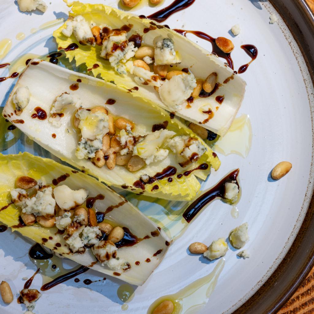 Barchette di indivia con erborinato vaccino, frutta secca e crema balsamica ai fichi