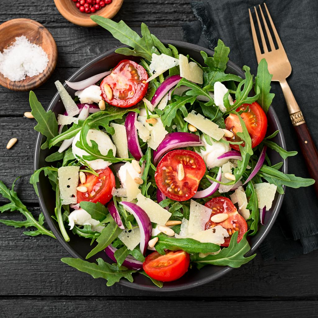 Insalata di rucola e pomodorini con scaglie di parmigiano reggiano di vacca bianca modenese e pinoli tostati